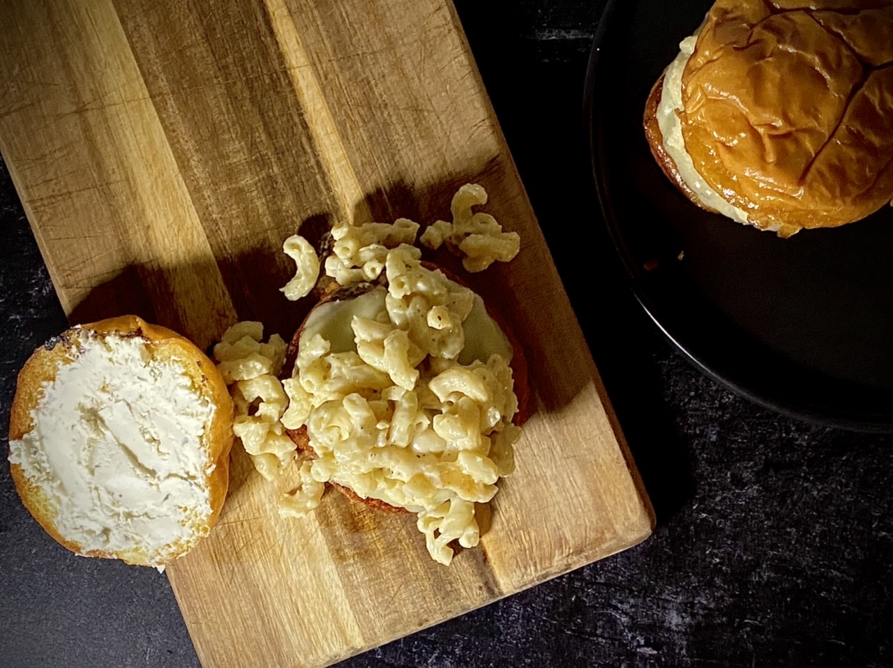 Macaroni and cheese burger on top of a wooden cutting board