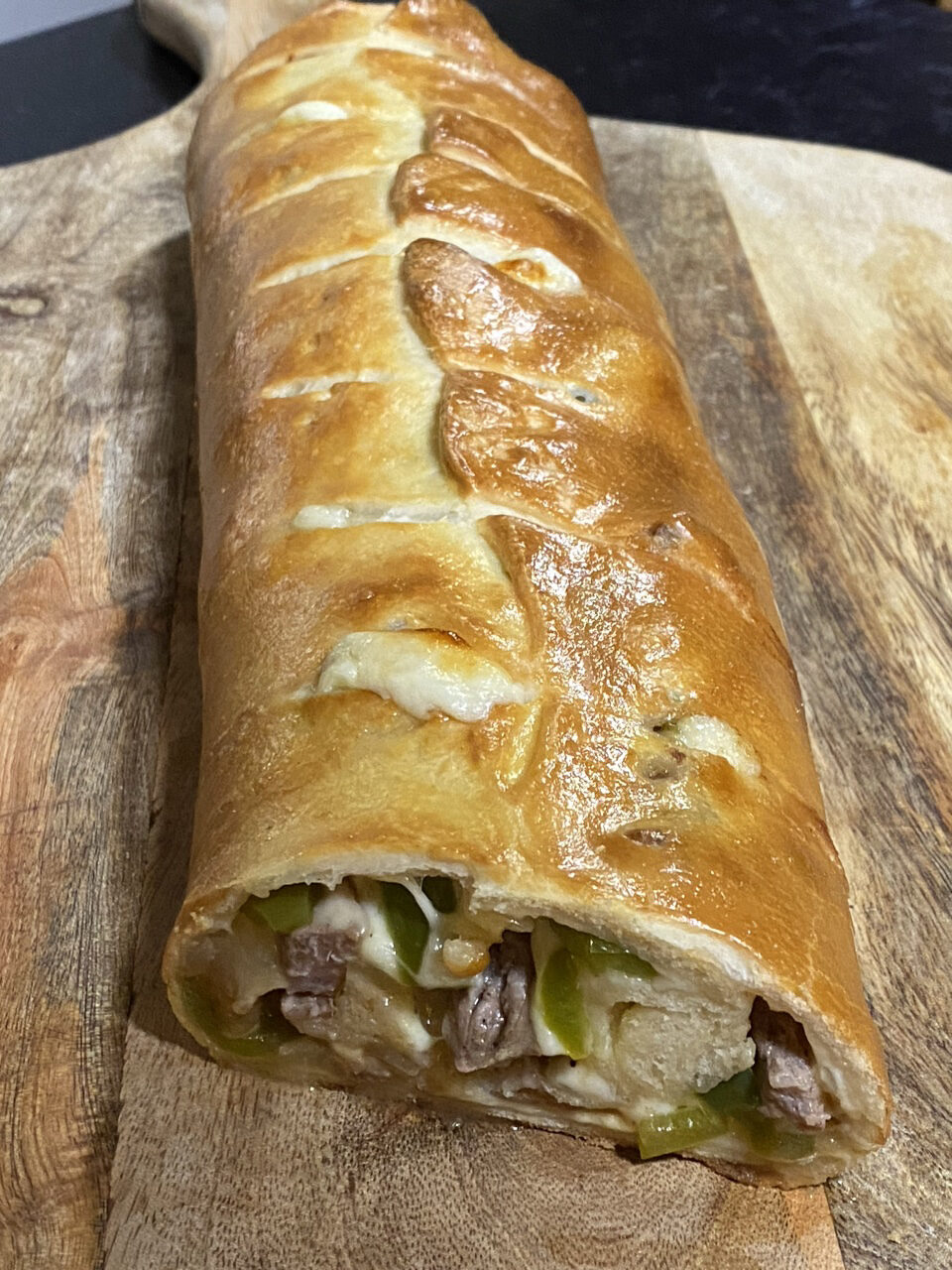 Philly cheesesteak Stromboli on top of a cutting board