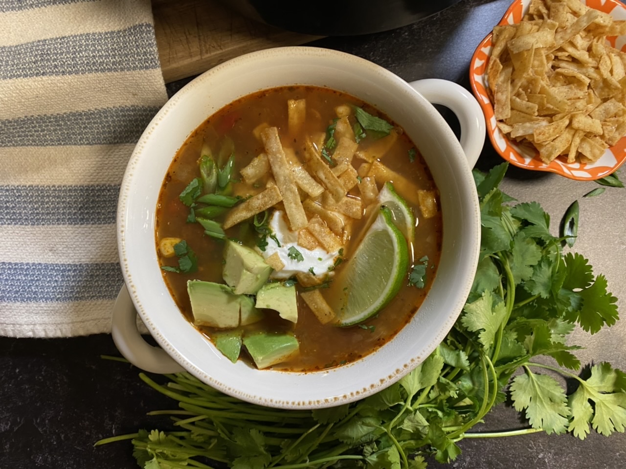 Chicken tortilla soup in a bowl on a blue and white towel