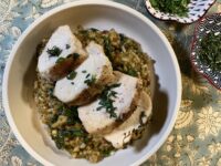 Sun-dried tomato pesto risotto with sliced chicken breast on a wooden cutting board