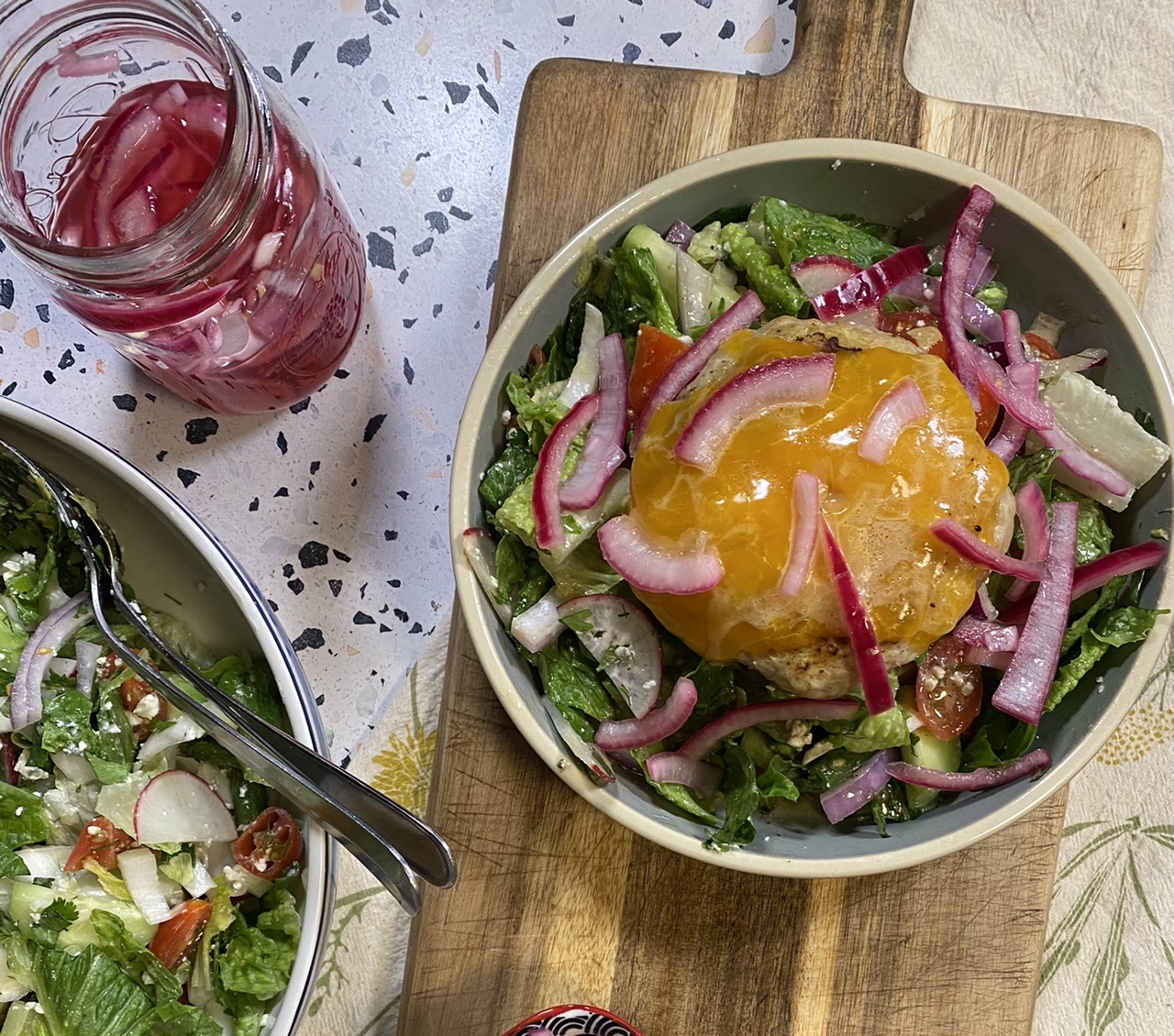 Salad bowl with a chicken burger in a bowl on top of a wooden cutting board