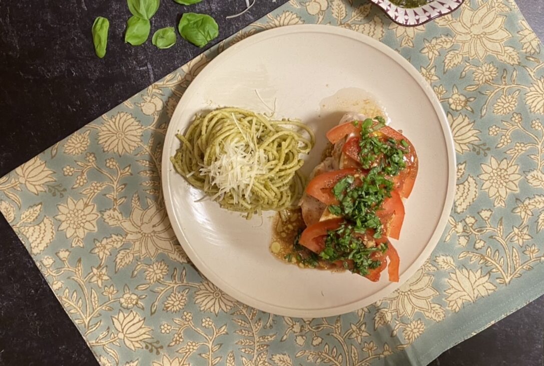 Caprese chicken and pesto pasta on a white plate