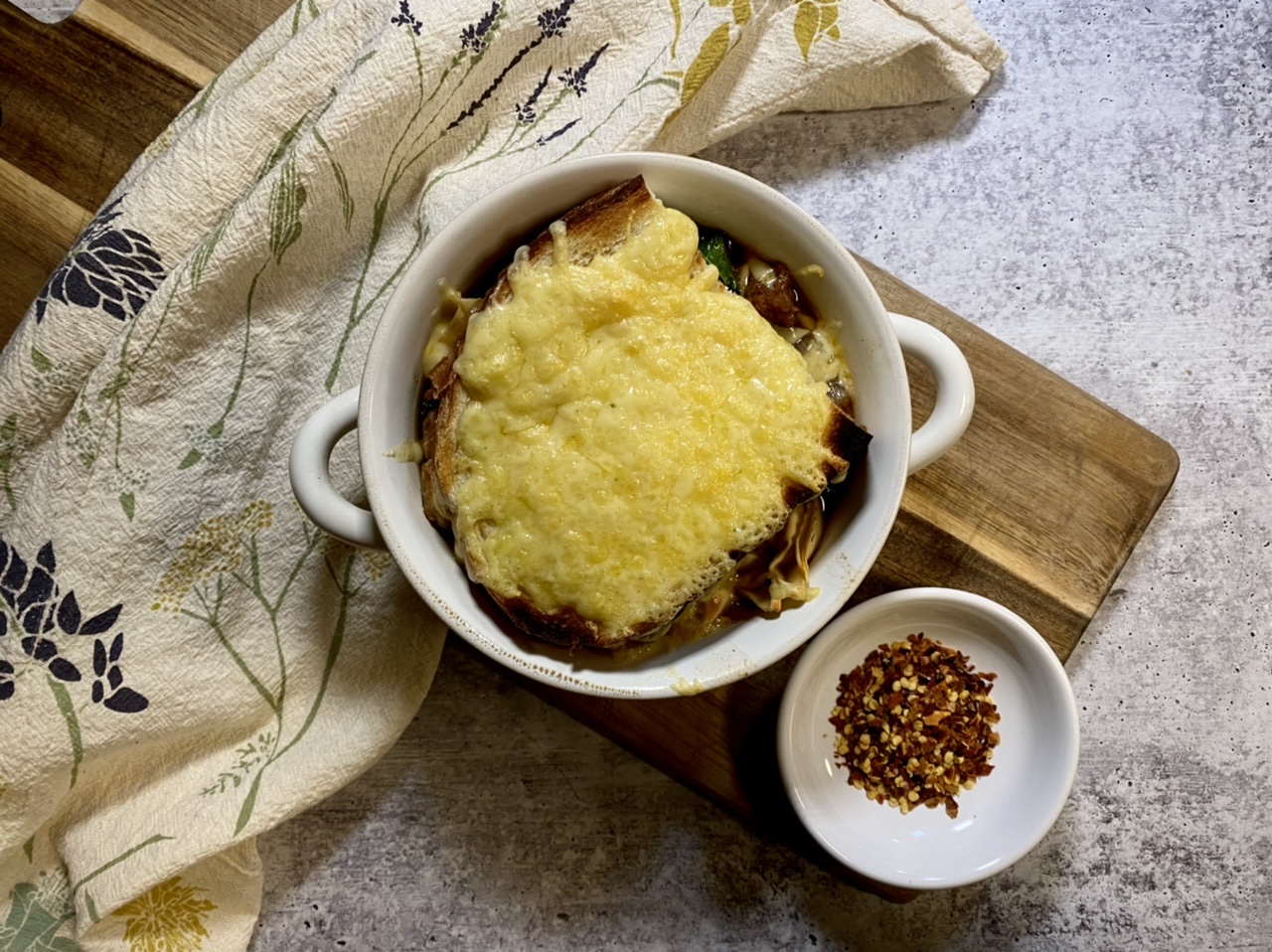 French onion soup in a white bowl on top of a cutting board