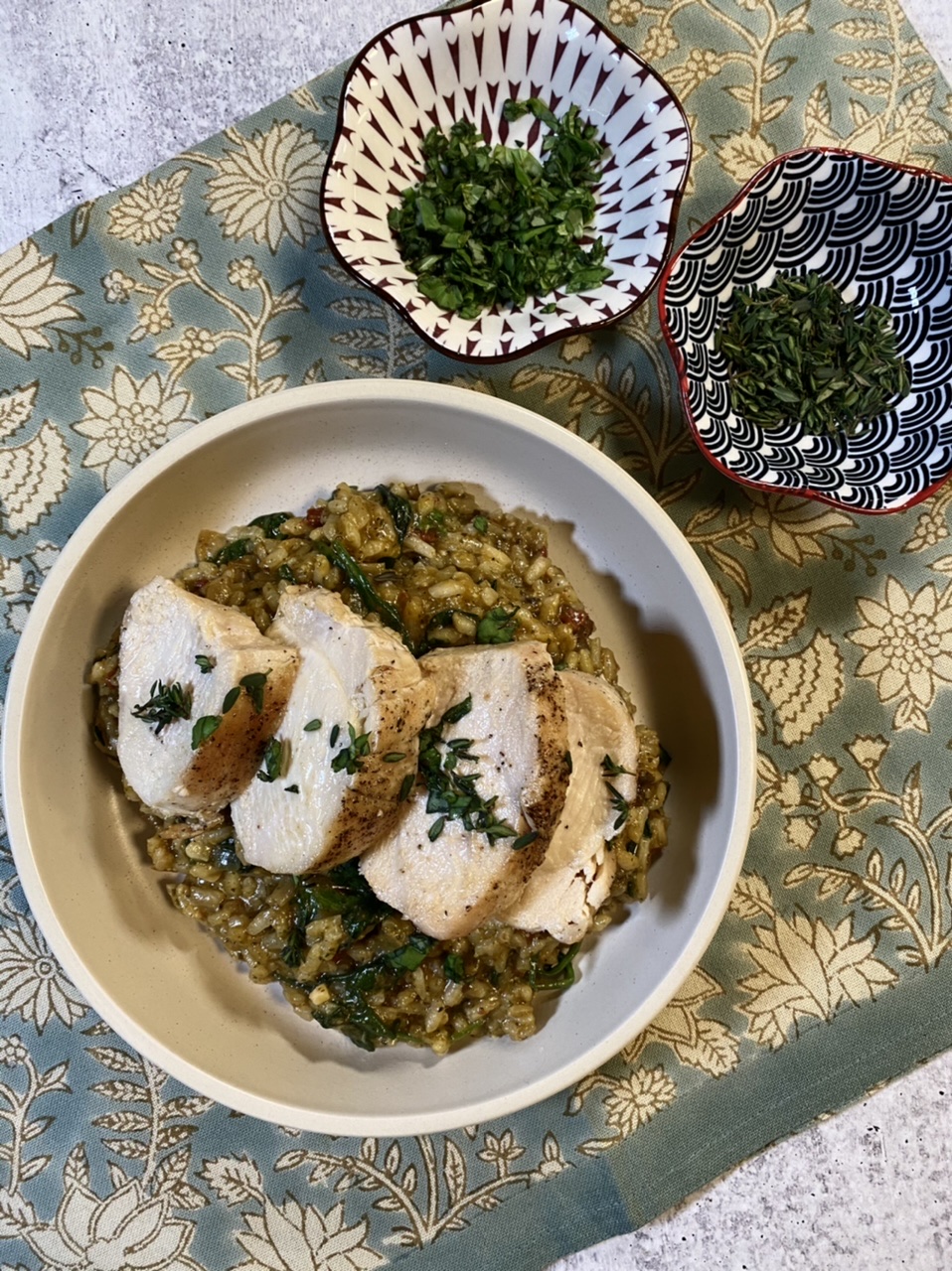 Sun-dried tomato pesto risotto with sliced chicken breast on a wooden cutting board