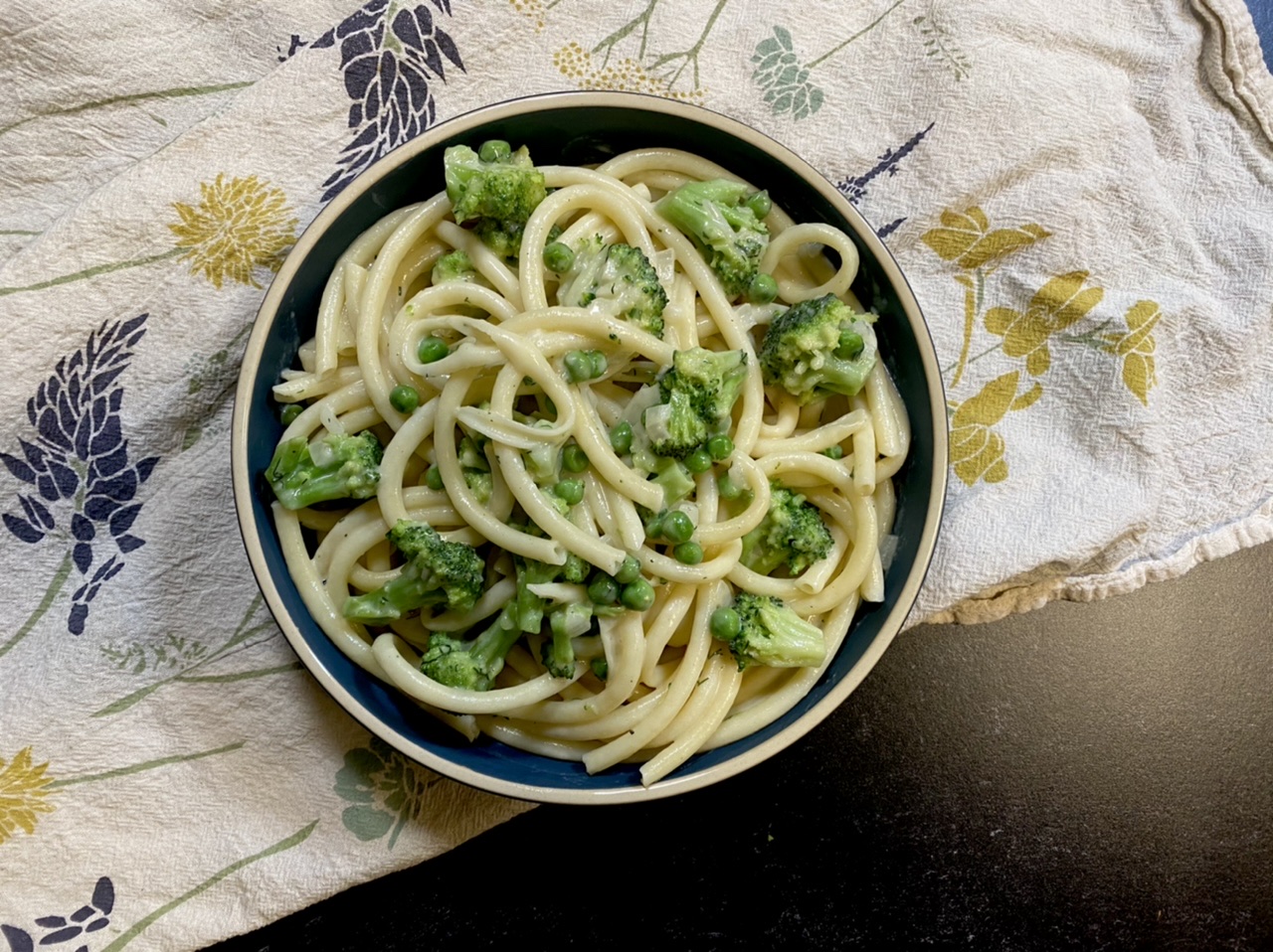 Mustard cheddar vegetarian pasta with broccoli and peas in a bowl on top of a white towel