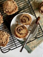 Coffeecake Nutella muffin on a white plate with a knife surrounded by muffins on a wire rack