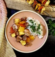 Hawaiian chicken, pepper, and pineapple kebabs with coconut rice on a pink plate