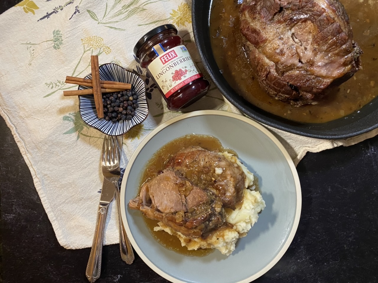 Roast pork on top of mashed potatoes with lingonberry gravy on top of a blue plate