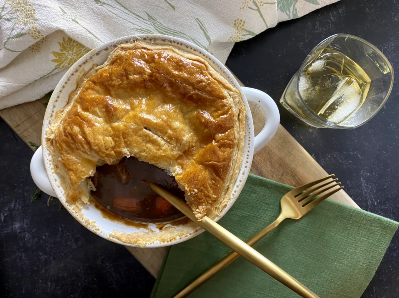 Beef and Guinness pie in a white bowl with a golden matte spoon