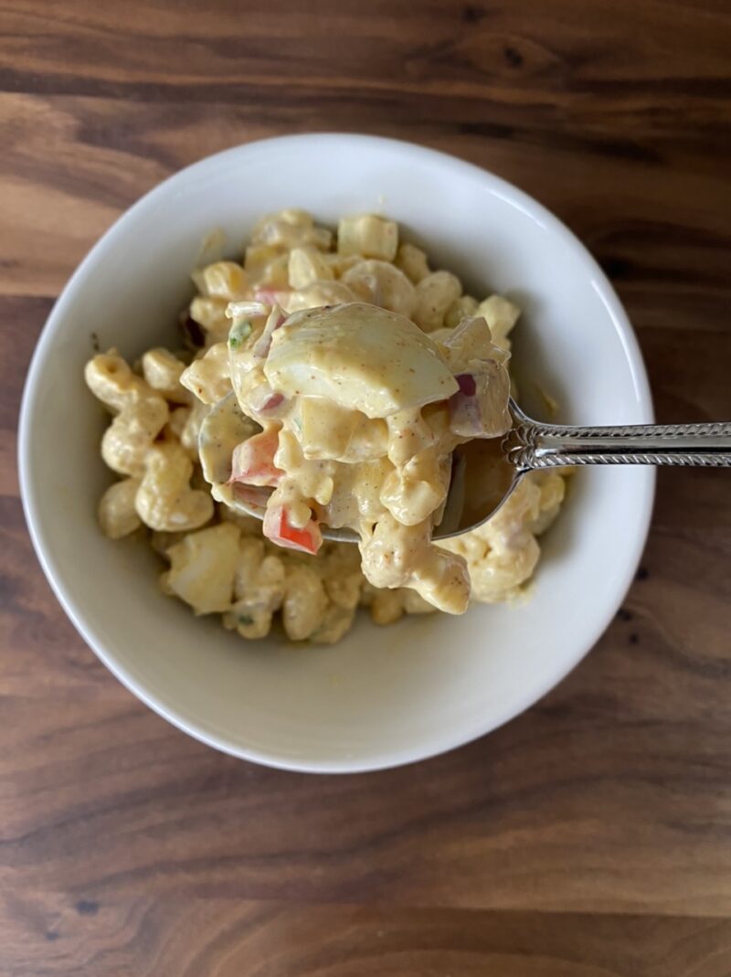 Tex-mex style pasta salad in a small bowl on top of a wooden cutting board