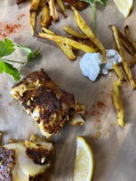 Indian fish and turmeric French fries on parchment paper with tzatziki and lemons