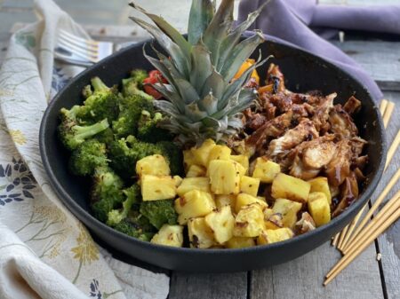 Grilled teriyaki chicken and vegetables and pineapple in a black bowl