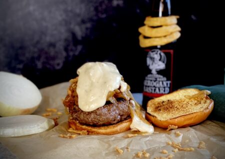 French onion burger next to a bottle of arrogant bastard beer