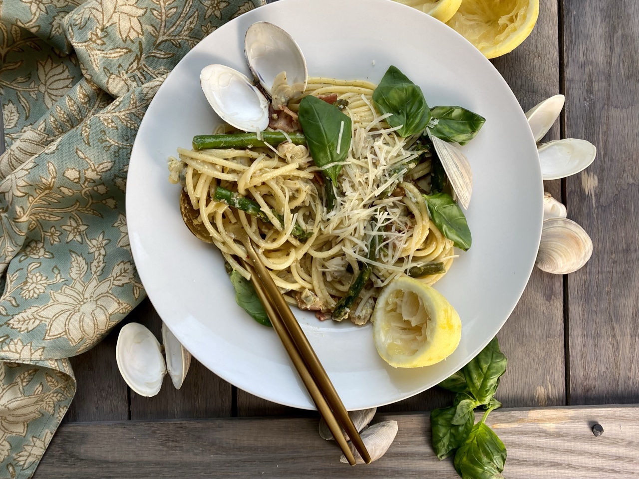 Clams and pesto bucatini with lemons and basil in a white bowl