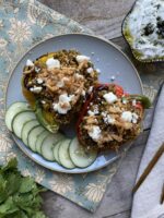 Lebanese mujadara stuffed bell peppers with cucumbers and labneh on a blue plate next to gold silverware and cilantro
