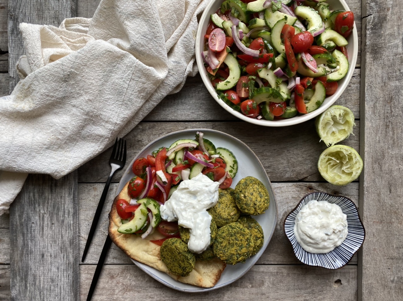 Indian curry falafels with Indian cucumber salad with a bowl of tzatziki on wooden boards
