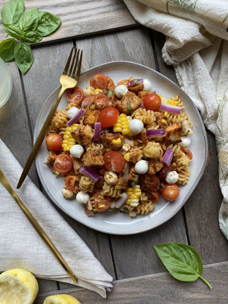 Blackened chicken antipasti pasta salad on a light gray plate